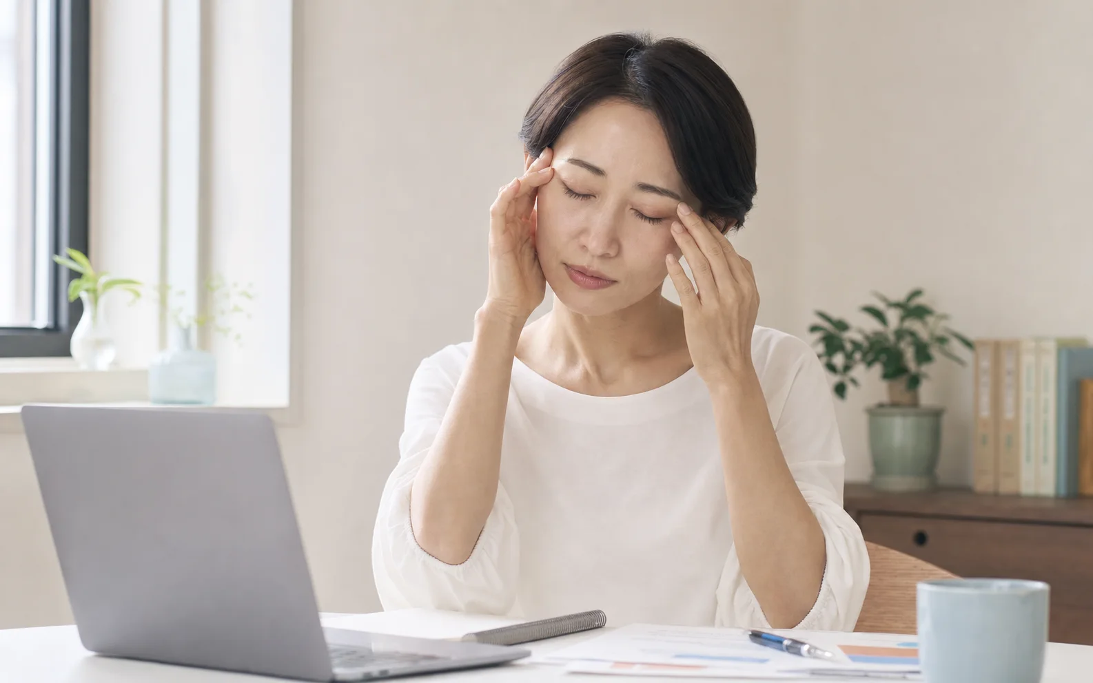画面作業中にこめかみと目の周りの重さを感じている女性