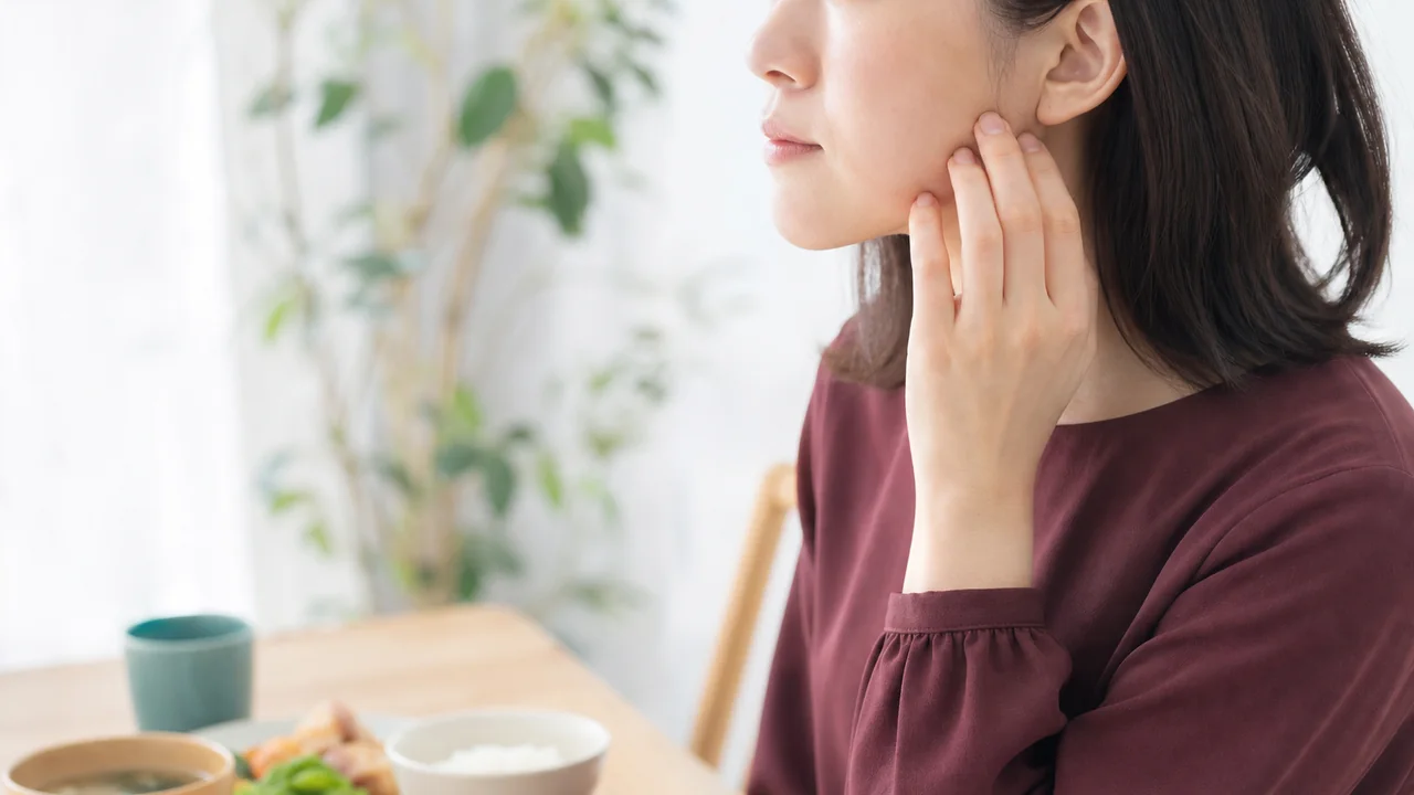 食事の前に耳の前の顎まわりへ指を添える様子